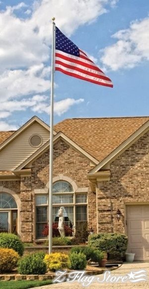 A large american flag flying in front of a brick house.